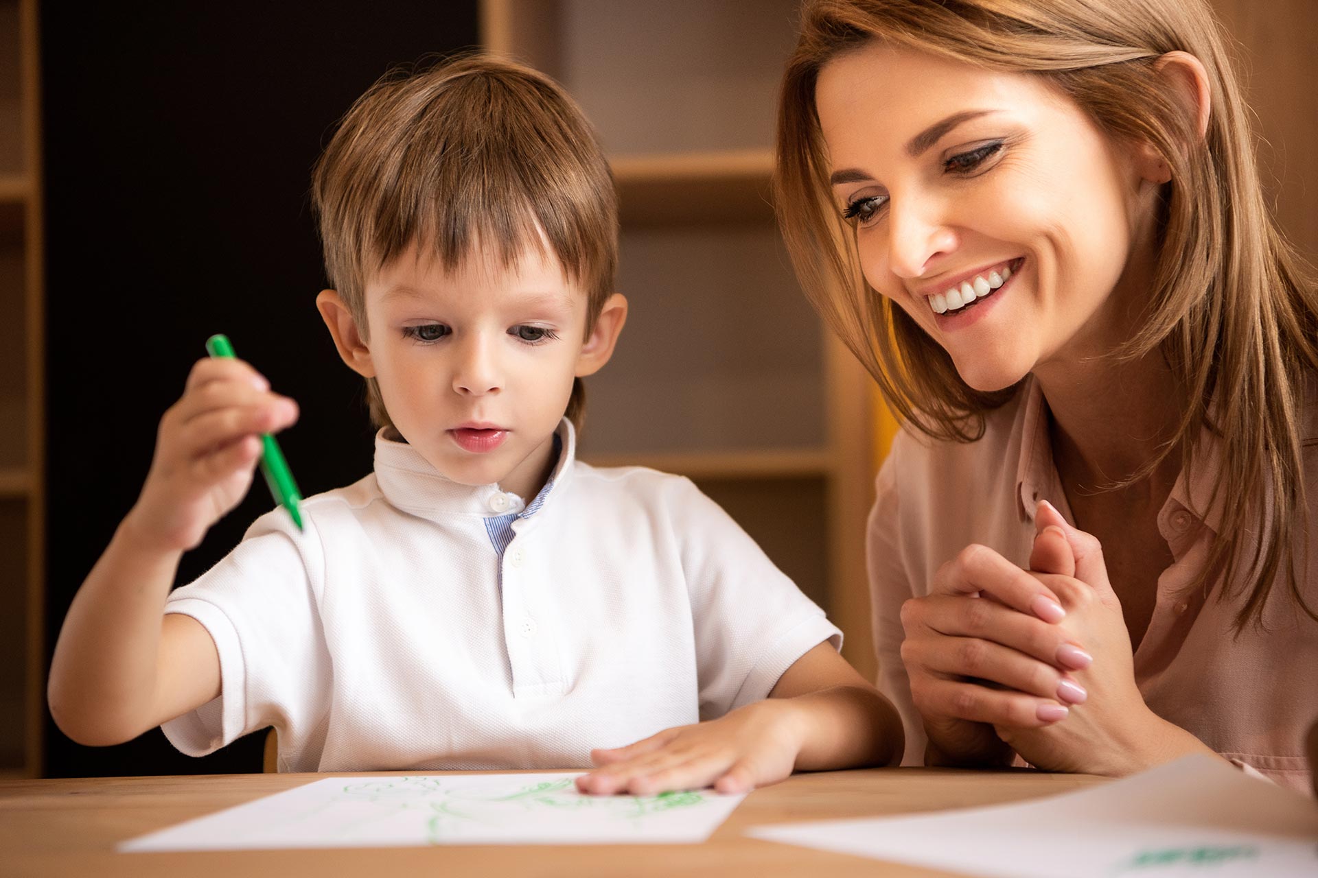 smiling educator looking at boy drawing in kinderg 2022 11 02 02 22 09 utc